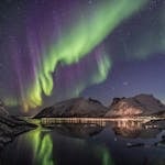 Beautiful aurora borealis over a snow-capped mountain lake at night with stunning reflections.