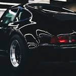 Elegant classic black car with shiny chrome and rear lamp visible in an indoor setting.
